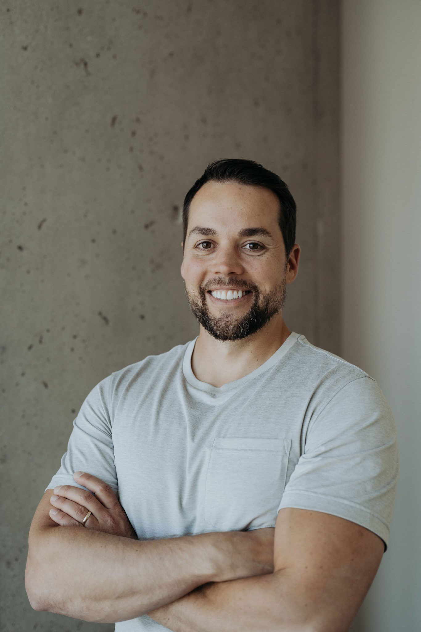Mike Munroe, smiling, arms crossed, in a light grey T-shirt